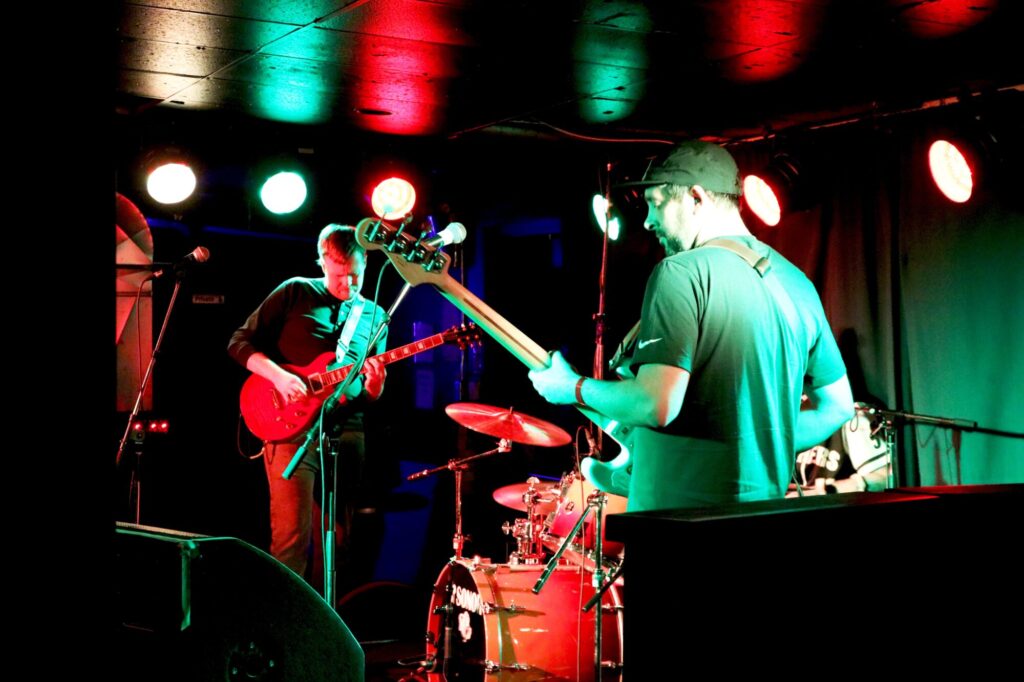 Photo of a band performing inside under red and green lights during the February 2025 Long Weekend Band Crawl in Waterloo, Ontario.